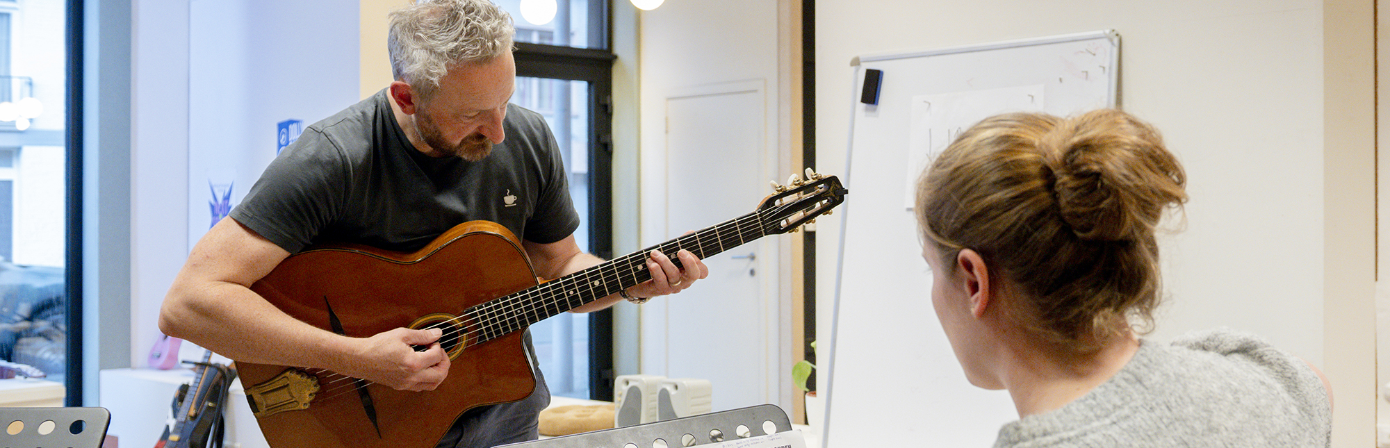 Eeklove-Dolly Dagger-23 Sven Bauwens geeft uitleg met een gitaar in zijn handen aan een leerling.